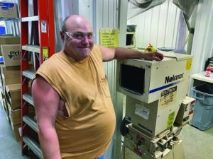 Joey Affolter poses in front of a plastics grinding machine