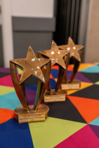 Three award trophies on a multicolored tablecloth.