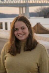 woman with long brown hair and cream colored sweater posed for picture, smiling