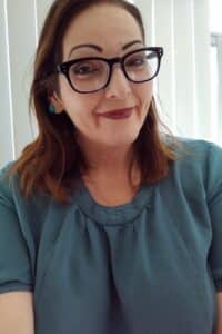 Woman with glasses in front of window blinds