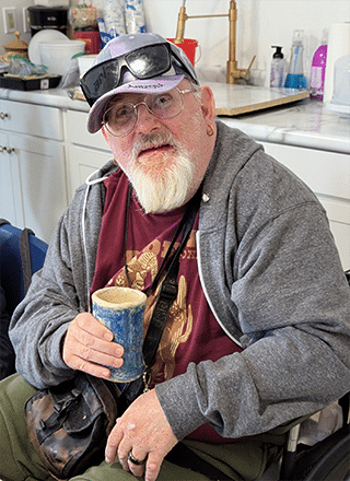A person served by Rise at a ceramics class, smiling and holding up the mug they created.