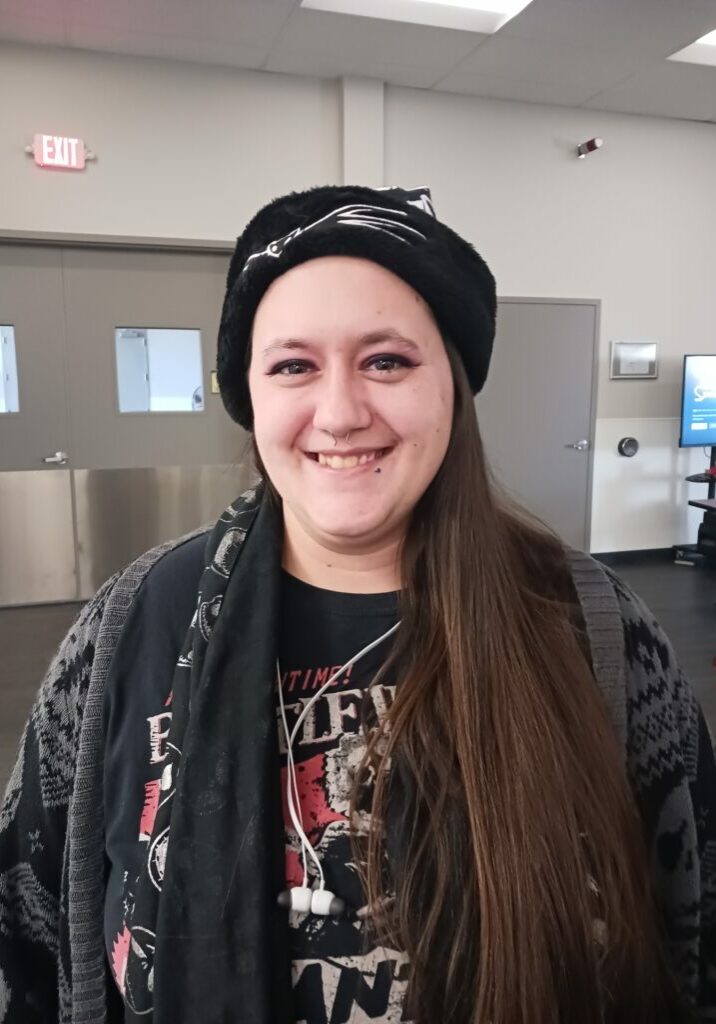 Jacki Fitzsimons, a white woman with long brown hair, wears a headband and sweatshirt. She smiles for the camera.