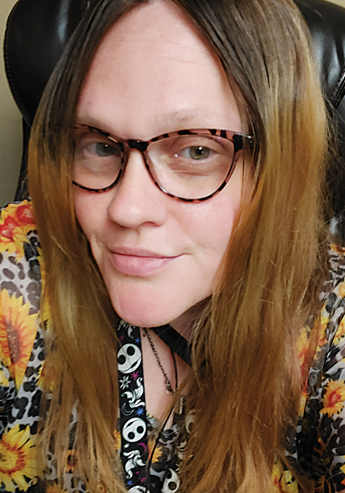 Headshot of Meleah Gore smiling wearing a sunflower printed shirt and glasses.