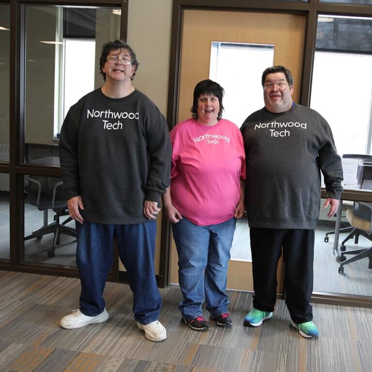 Three people on a Rise team stand together and smile. All wearing shirts that say 'Northwood Tech'.