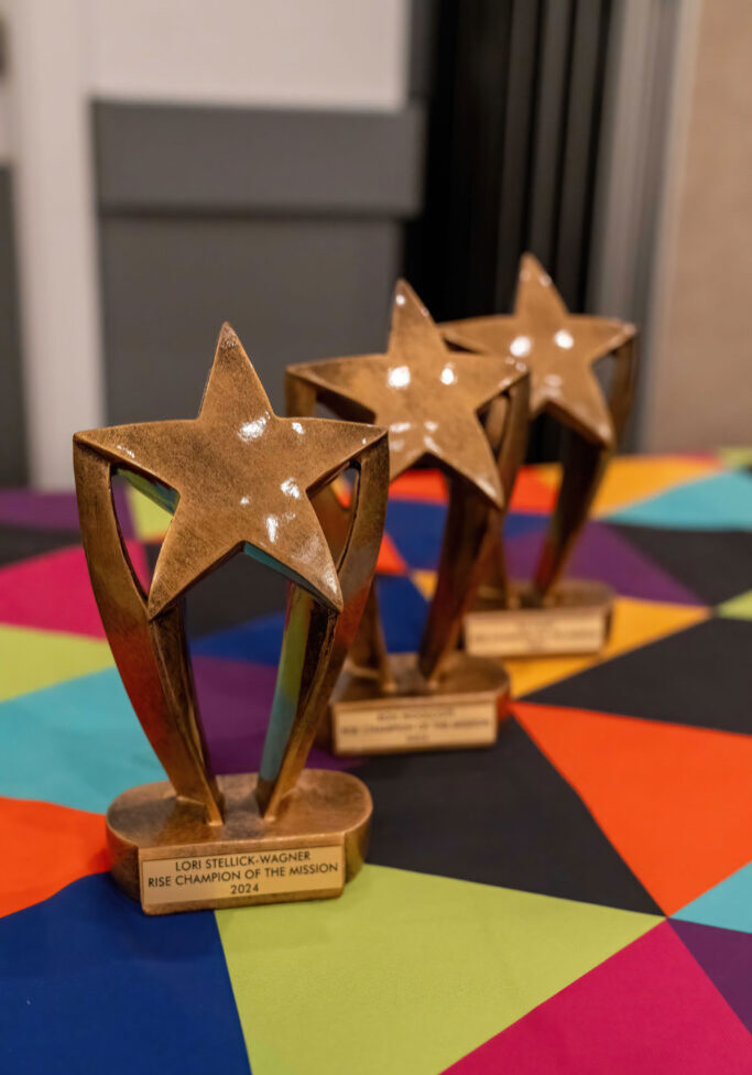 Three award trophies on a multicolored tablecloth.