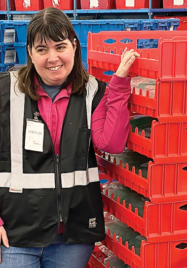 Jenny Wood smiles while pulling red crates stacked on one another.