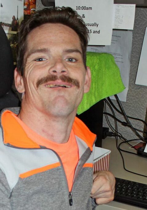 work support services guy at desk next to computer