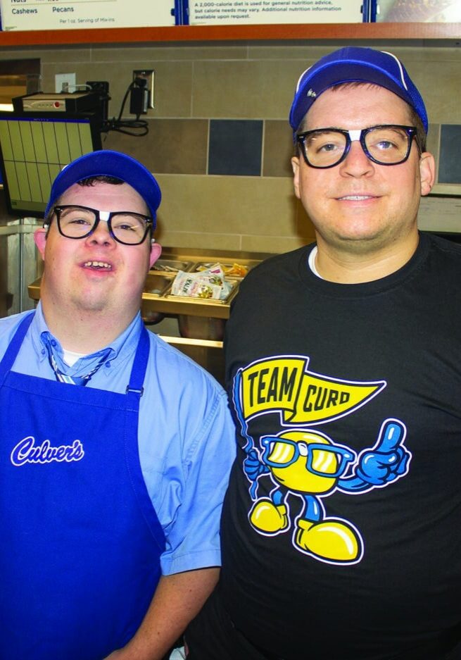 Wes Dahle stands next to Mark Riggins as they smile wearing their Culvers work attire at the Culvers in Woodbury.