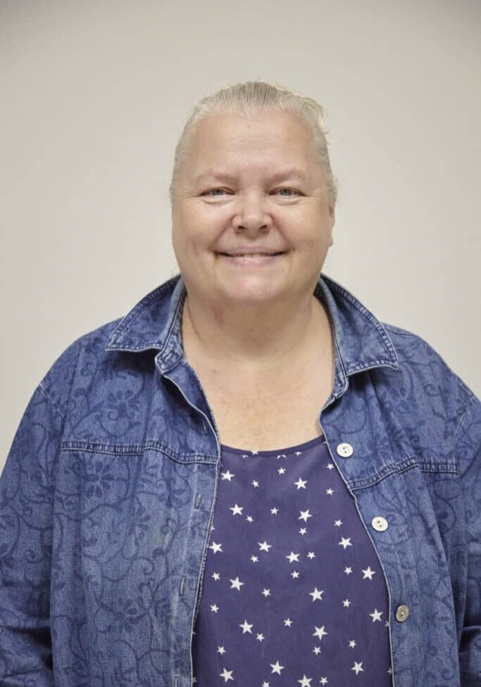 Headshot of Dawn Moder, wearing a blue shirt, in front of white wall