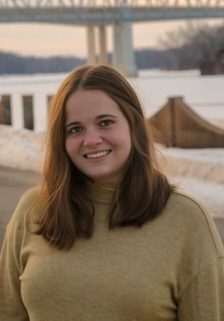 woman with long brown hair and cream colored sweater posed for picture, smiling