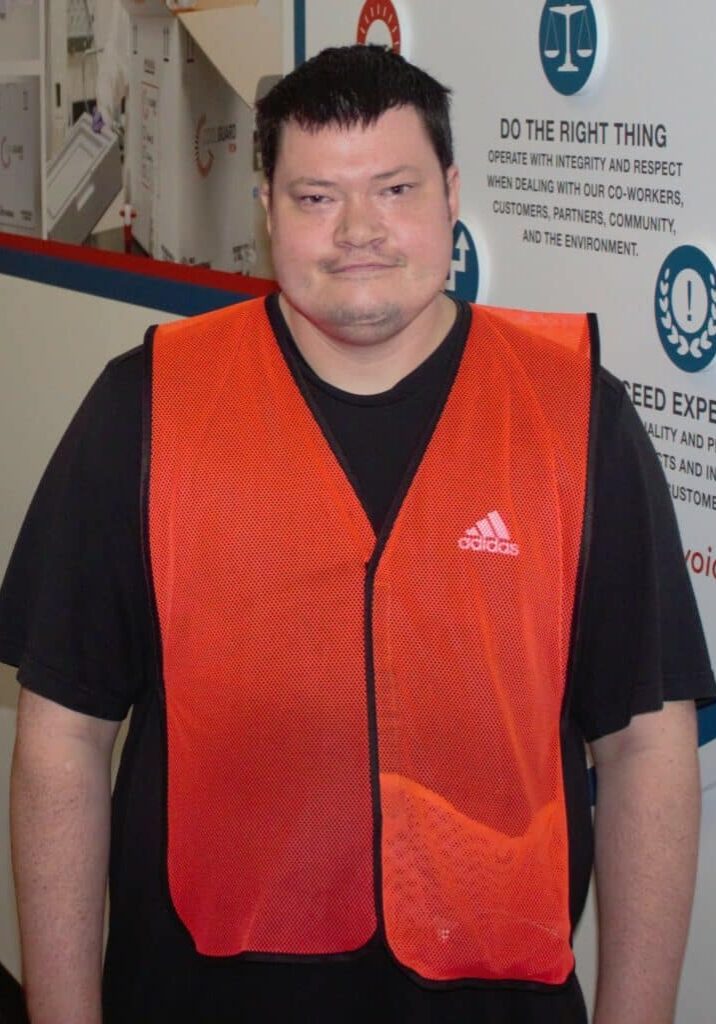 Jordan Rock stands at his worksite wearing a bright orange vest.