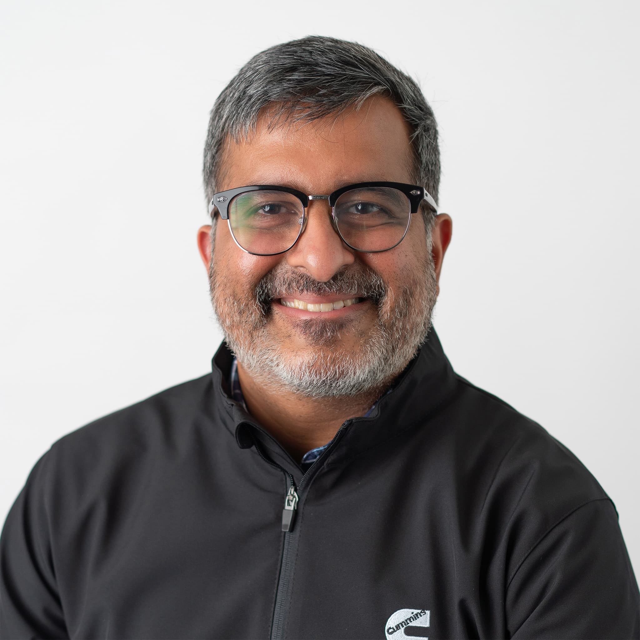 Krishna smiling at the camera with a black top and glasses.