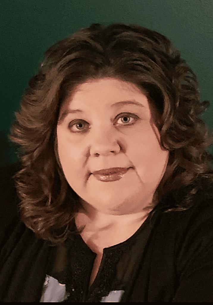 Michelle Andrews smiling headshot in front of a dark green wall.