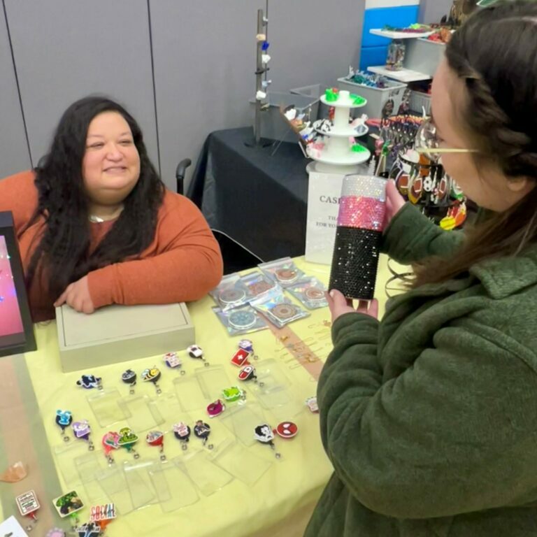 Rachel Dolan speaks with a customer at a craft fair for her business, Rachel's Bling N' Thingz