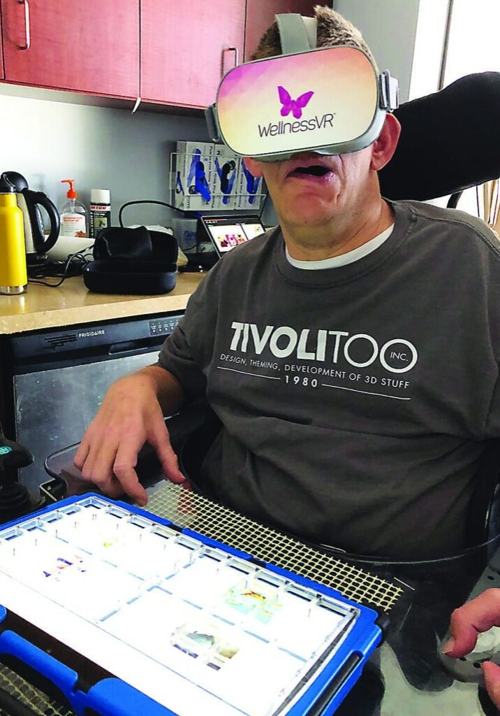 Wendell Eric Peterson wears a VR headset while sitting in his wheelchair.