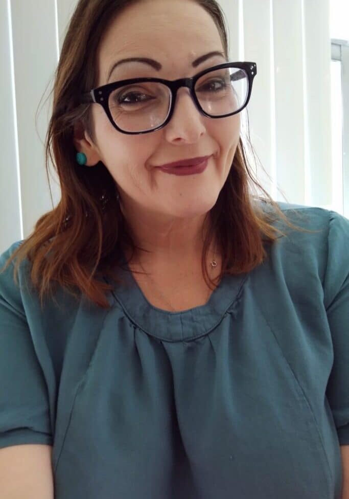 Woman with glasses in front of window blinds