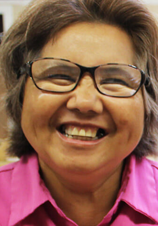 About Rise - Tan woman with brown hair and glasses wearing a pink shirt smiles for the camera.