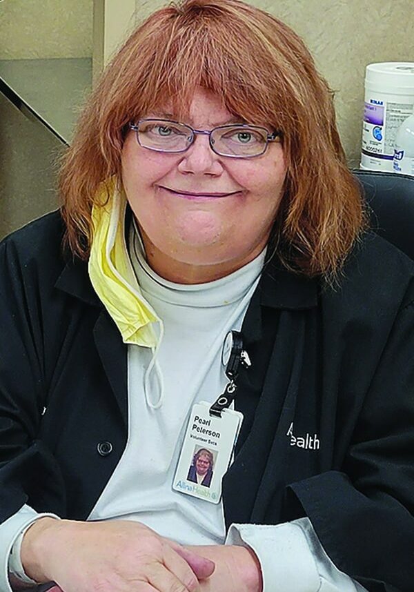 Pearl Peterson smiles wearing glasses, a white top, and black sweater.