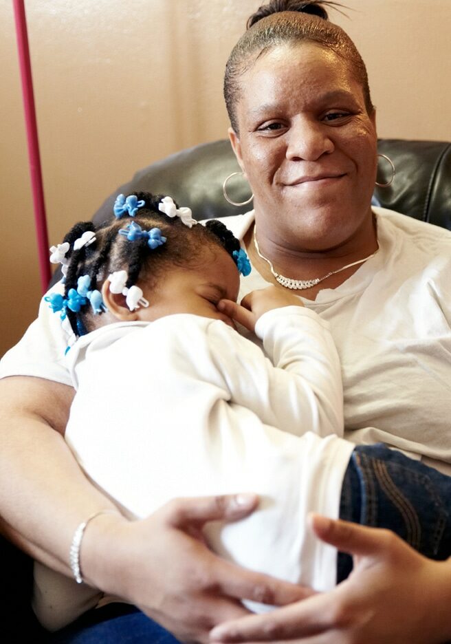 Black woman in a white shirt takes care of her toddler