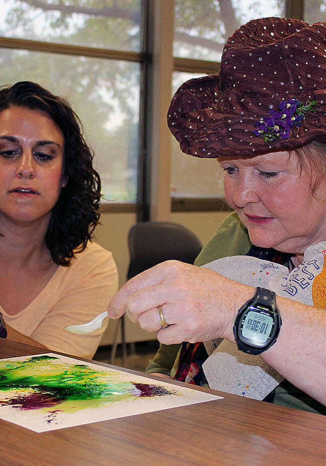 Rise Art Therapist Stacy Gross helps person served with a water color art activity.